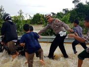 Salah seorang petugas Polisi Lalulintas tampak sedang membantu pengendara yang melintasi banjir di jalan raya, Selasa hari ini (24/4/2018). (Foto/Arief H)