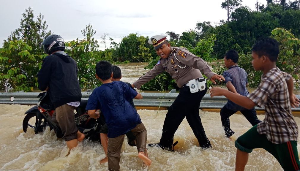 Salah seorang petugas Polisi Lalulintas tampak sedang membantu pengendara yang melintasi banjir di jalan raya, Selasa hari ini (24/4/2018). (Foto/Arief H)