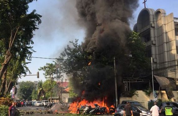 Api dan kepulan asap tebal membumbung di udara beberapa detik setelah ledakan di depan Gereja GKI Surabaya, Minggu pagi (13/5/2018). (Foto/Ist)