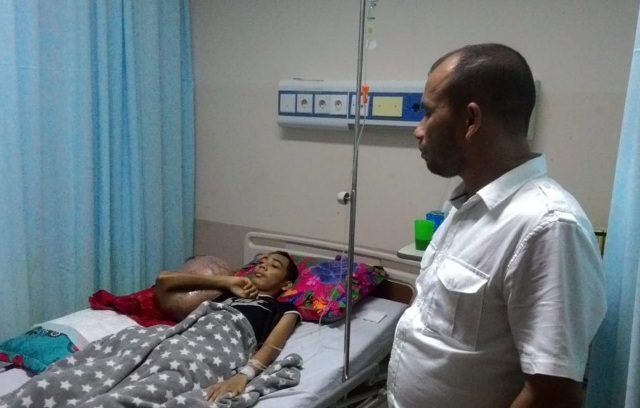 PHOTO-2018-06-30-14-11-44 Ketua PMI Kota Lhokseumawe Junaidi Yahya saat menjenguk Hendrizki,19, warga Seunudon, Aceh Utara, di Rumah Sakit Umum Zainal Abidin, Banda Aceh. (Foto/Ist)