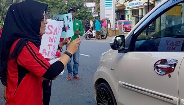 IMG-20181202-WA0004 Seorang wanita petugas Dinas Kesehatan Pidie dari Puskesmas Padang Tiji sedang membagi-bagikan stiker bertuliskan Say No HIV/Aids kepada warga. Kegiatan itu bagian dari peringatan hari HIV/AIDS sedunia setiap 1 Desember. (Foto/Muhammad Riza)