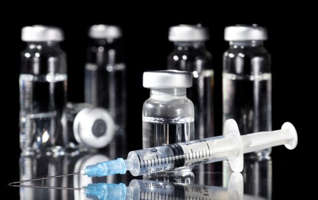 Glass Medicine Vials and Syringe on black background
